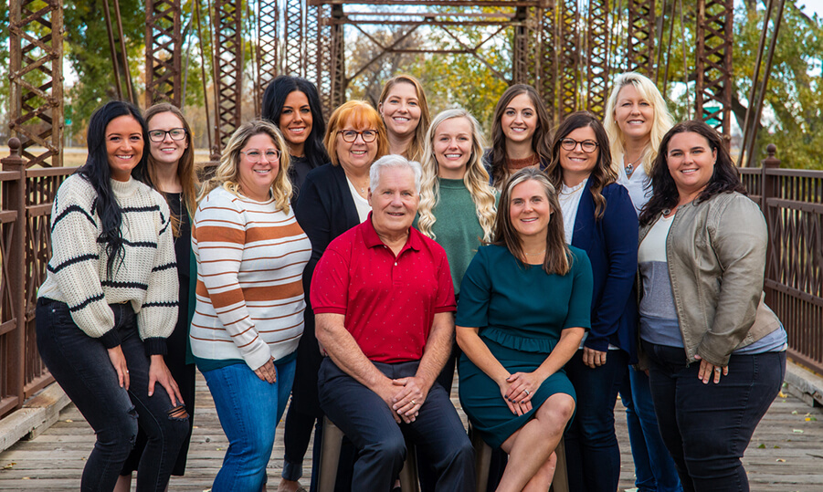 The dental team at Horner Barrow Orthodontics, PC. posing together on a wooden bridge in front of a park in Sioux Falls, SD.